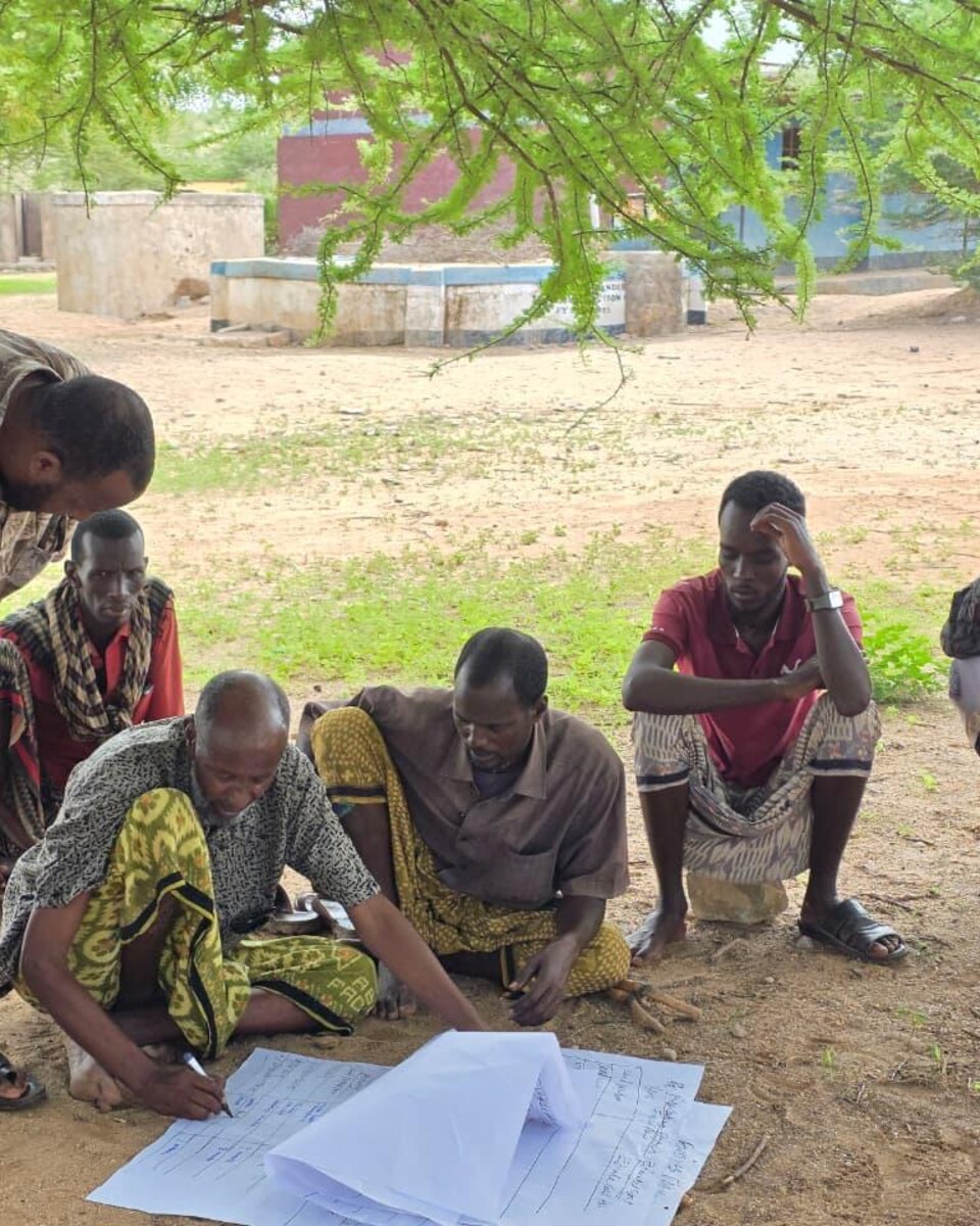 APCINE field team facilitating a participatory community planning session under a tree in Northern Kenya