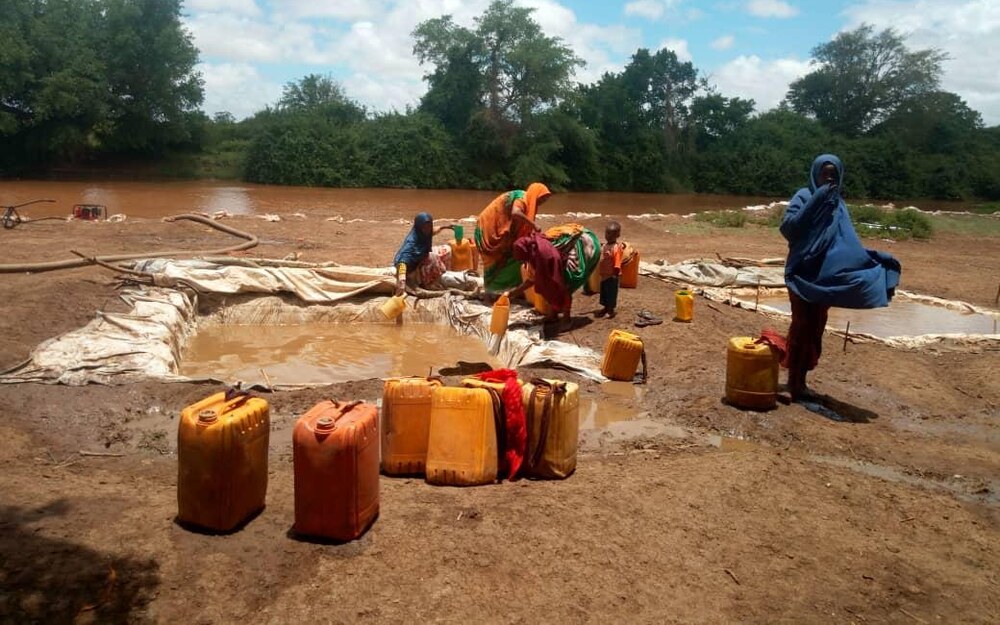 Women and children collecting water from a community water pan